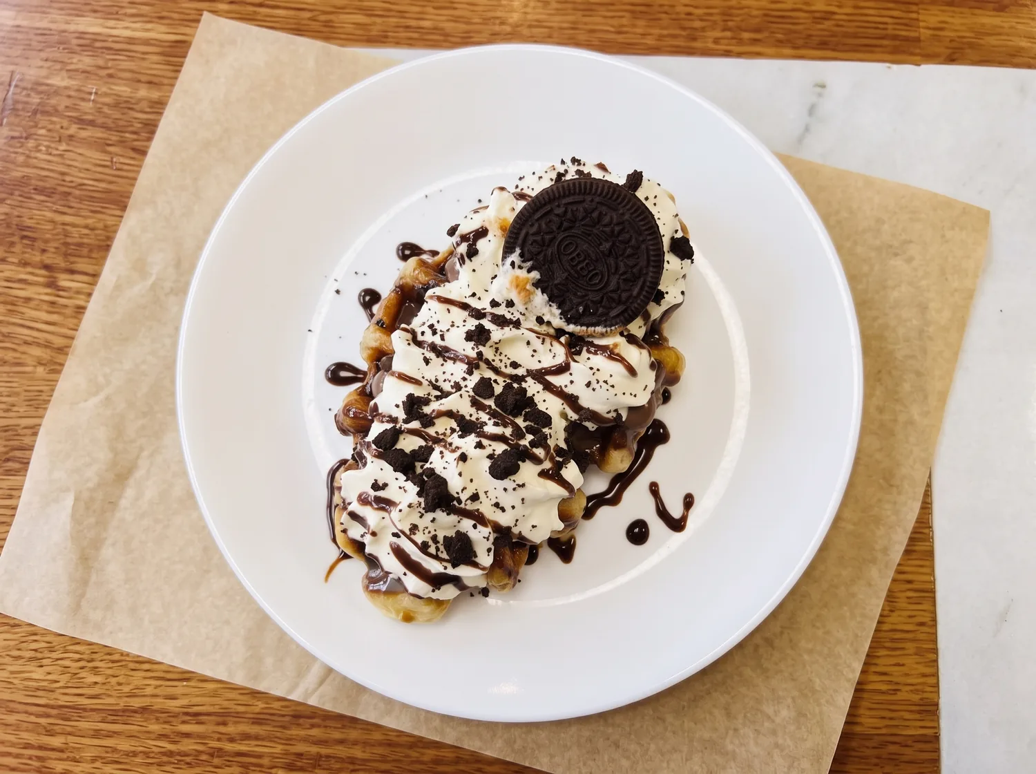 A croffle with Oreo, whipped cream and chocolate drizzle.