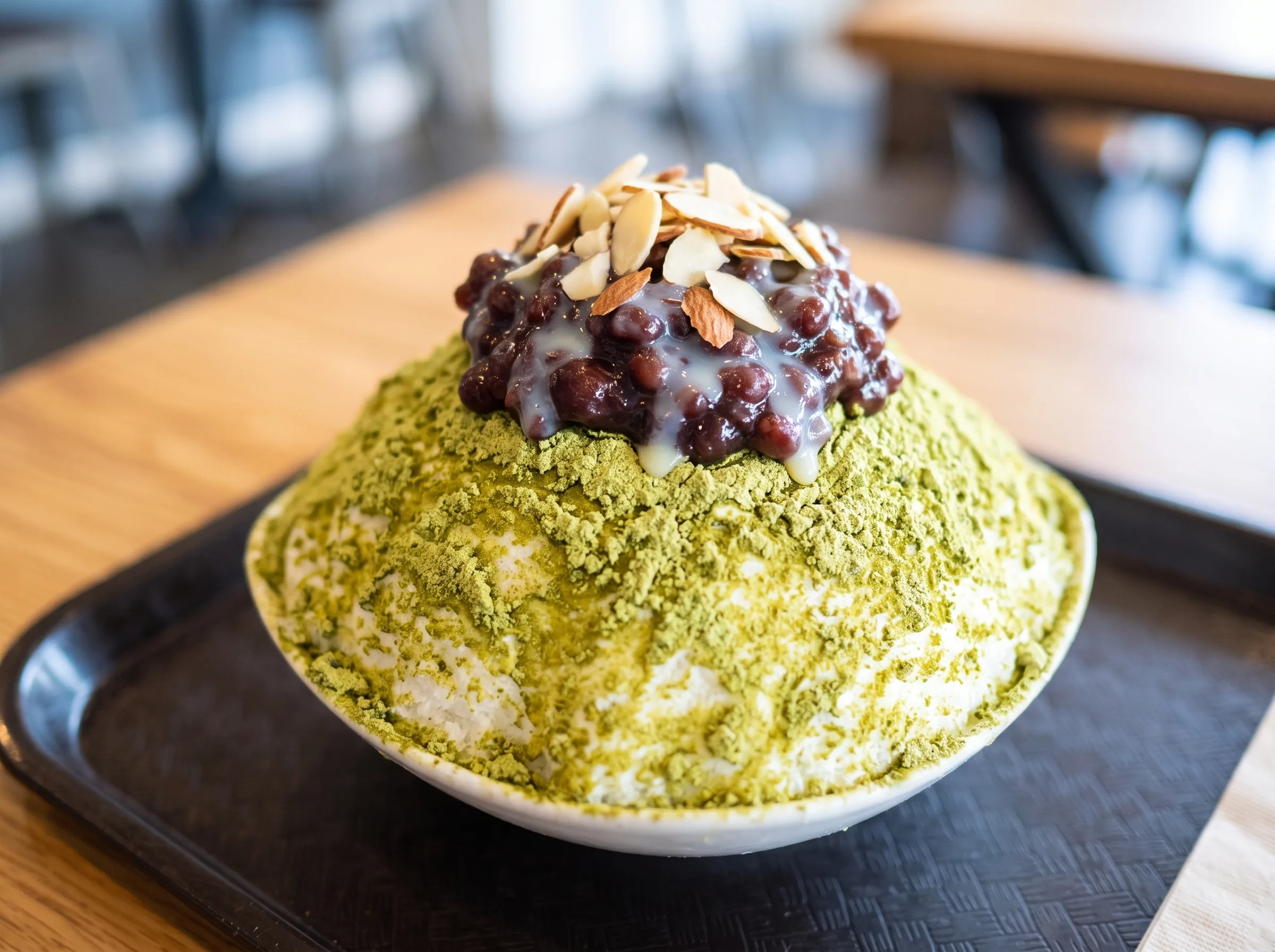 Green tea bingsu under red bean and toasted almonds.