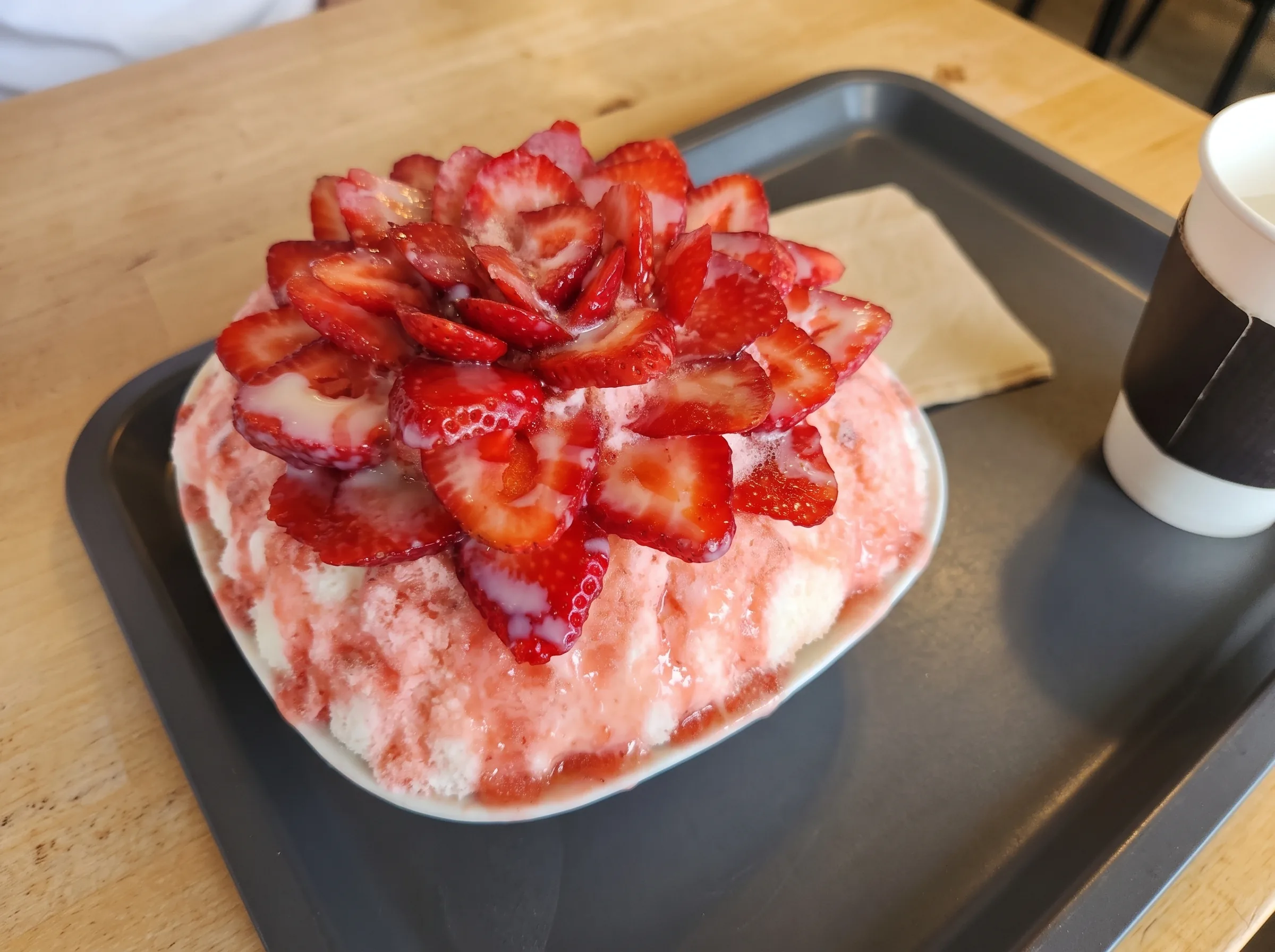 A mound of strawberry bingsu on a tray.